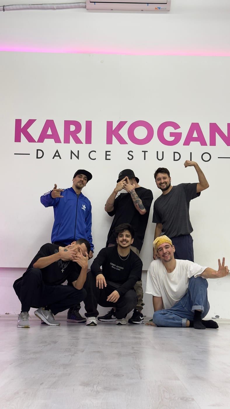 Eight dancers posing together in a mirrored dance studio