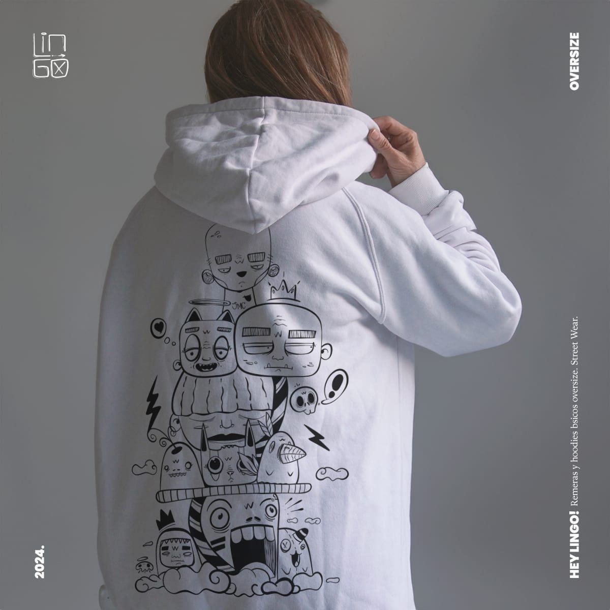 The back of a white oversize hoodie printed with the same stacked monster characters in outline