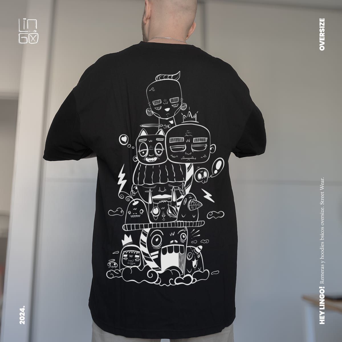 The back of a black oversize t-shirt printed with a stacked tower of hand-drawn monster characters
