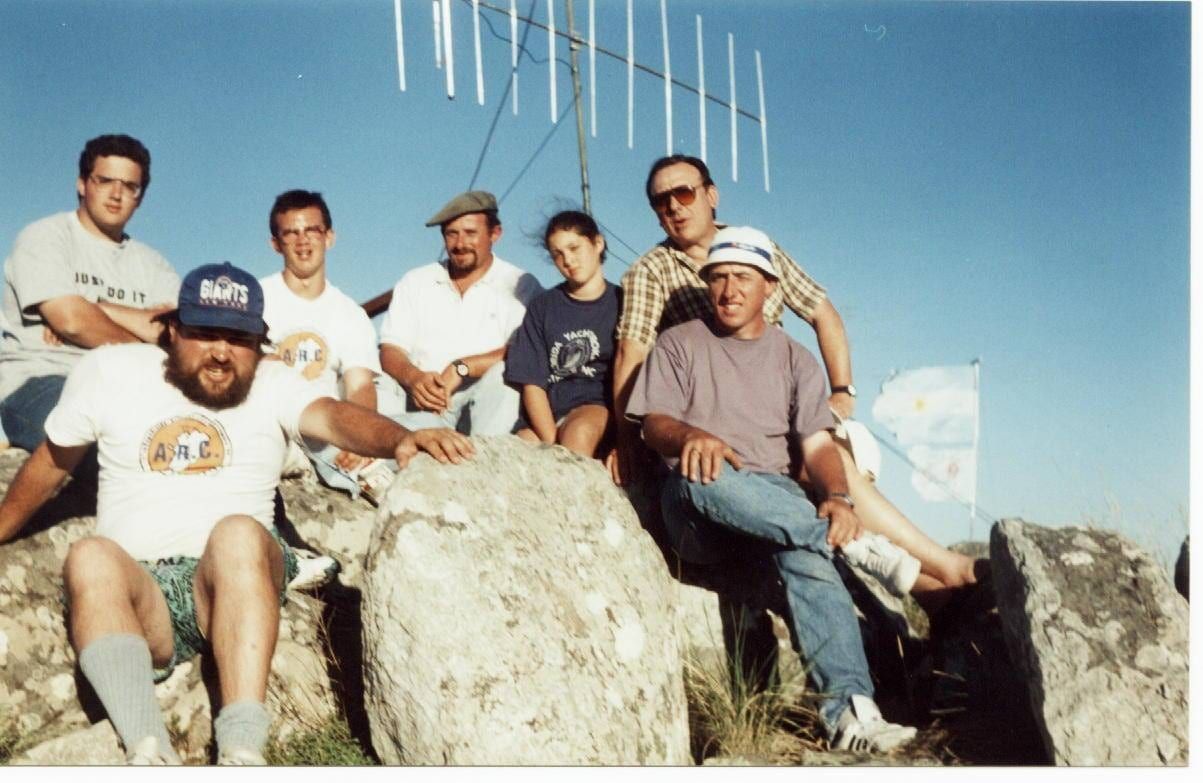 A group of radio operators outdoors on a hillside beside portable antenna masts