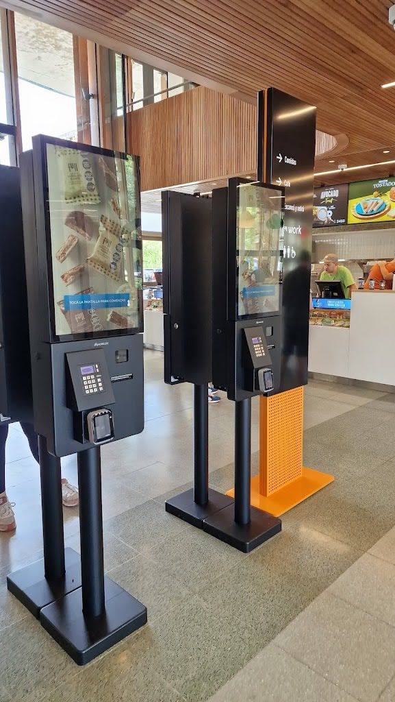 Several black self-service ordering kiosks installed inside a YPF Full store.