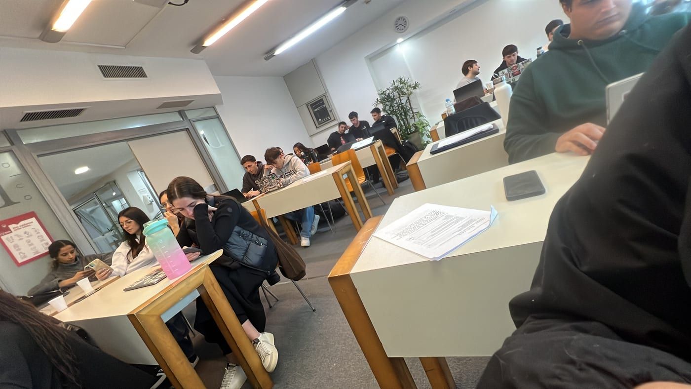 Students working at desks in a university room during a design session